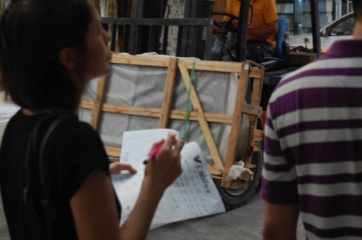 A shipment list being checked beside crated furniture at a loading area in China